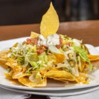 Loaded Chicken Nachos · Crispy baked tortilla chips piled high and topped with grilled chicken, smothered with cream...