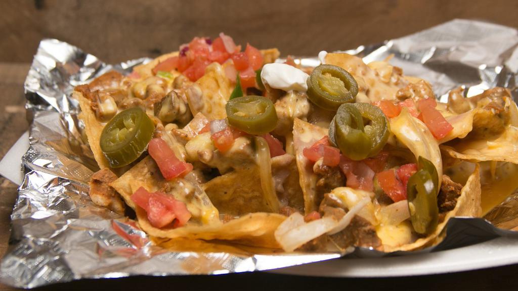 Nachos · Tortilla chips layered w/ beans, cheese & meat - side jalapeños & sour cream.