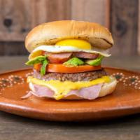 Hamburguesa De Desayuno / Breakfast Burger · Huevo, aguacate, tomate, queso, jamón, hamburguesa, y salchichas crujientes. / Egg, avocado,...