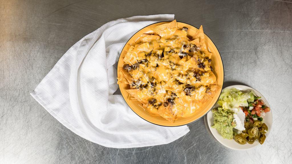 Nachos · Crispy tortilla chips topped with refried beans, your choice of meat, queso, and shredded cheese. Comes with a side of pico de gallo, sour cream, guacamole, and jalapeños.