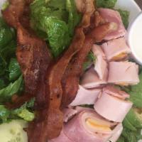 Chef Salad · Ham, turkey, bacon, and swiss cheese on a bad of lettuce, tomato, croutons, and choice of dr...