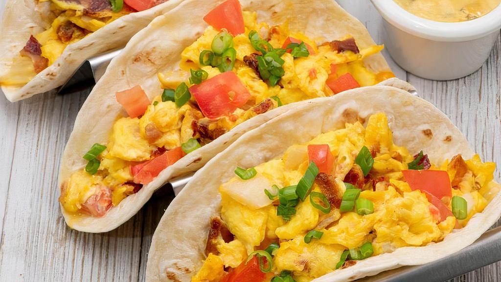 Breakfast Tacos · Stuffed with scrambled eggs, our thick bacon, fresh tomatoes, onion and aged cheddar cheese. Served 3 to an order with Homemade Salsa, Hacienda Hollandaise + choice of side