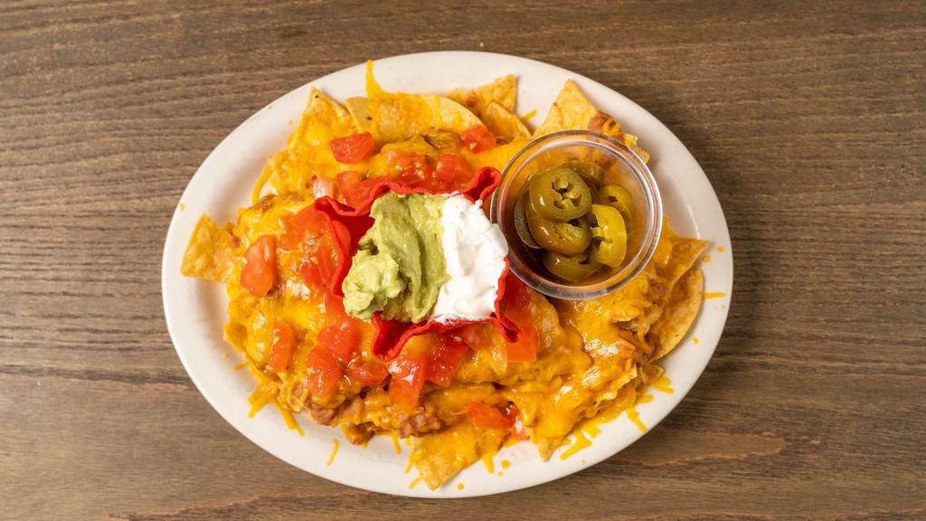 Nachos Supreme · Loaded corn chips with beans, ground beef, cheese, tomatoes, sour cream, guacamole and jalapeños on the side.