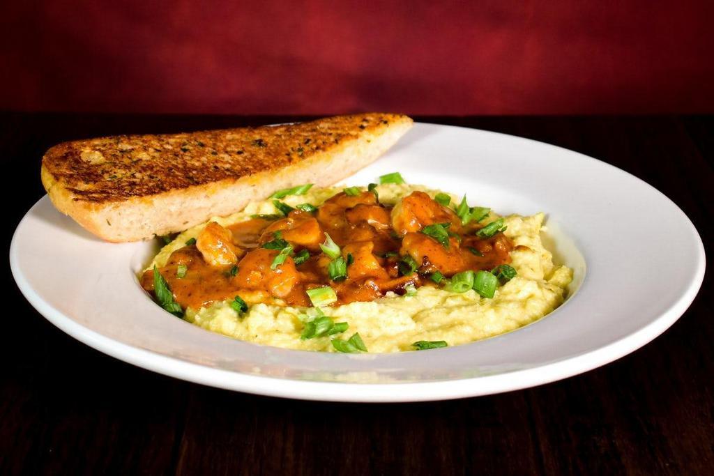 Shrimp & Grits · Green chili cheddar cheese grits topped with sautéed shrimp, bacon, mushrooms & green onions tossed in a tomato lobster cream sauce.