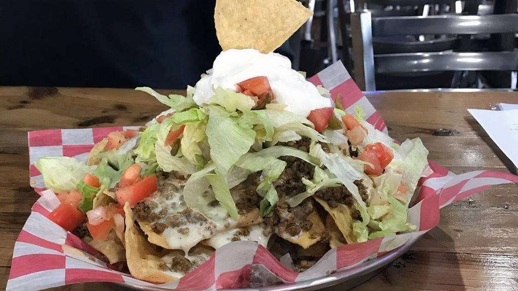 Big Ol' Nachos · A mountain of tortilla chips, topped with ground beef or fajita chicken,  2 layers of queso, pico de gallo and shredded lettuce.
