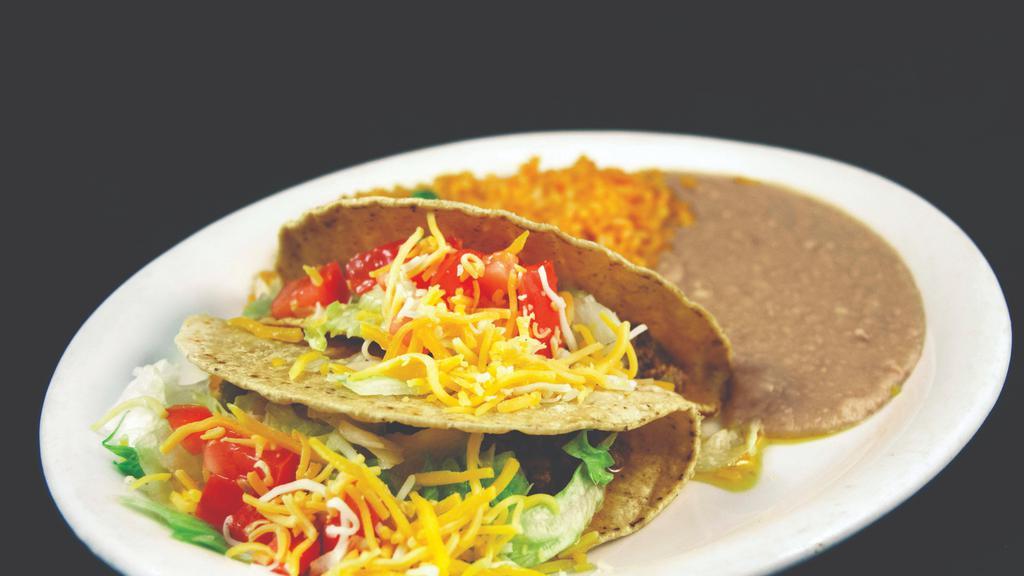 Tacos Plates · Three tacos on a large plate served with rice and refried beans.