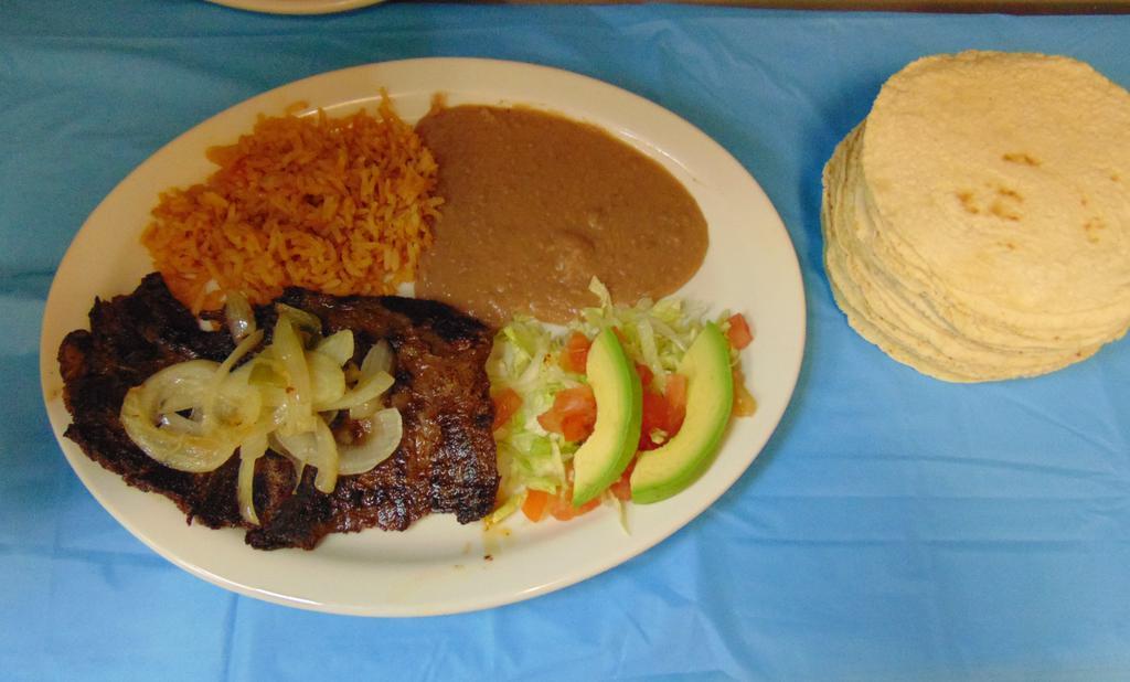 Carne Asada (Arrachera) · A marinated beef skirt steak topped with grilled onions and peppers, Served with beans, rice, and avocado slices.