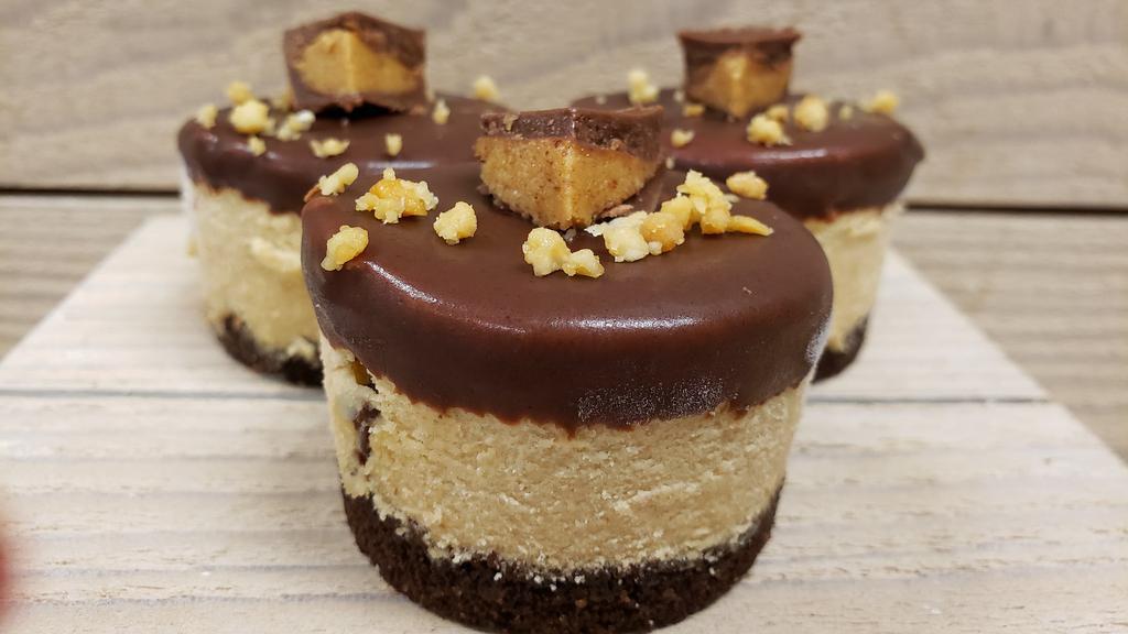 Peanut Butter Cup · Our peanut butter cheesecake with Peanut Butter Cup pieces inside, dipped in our chocolate ganache, sprinkled with bits of peanuts and topped with a Peanut Butter Cup piece; finished with a GF chocolate cookie crust.