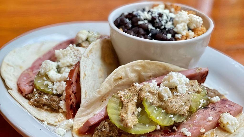 Cuban Pig Tacos · Have you ever had a Cuban sandwich in taco form?  We made it happen!  Our famous pulled pork is joined with ham, swiss, pickles & grain mustard on your choice of tortilla.  Served with rice and beans.