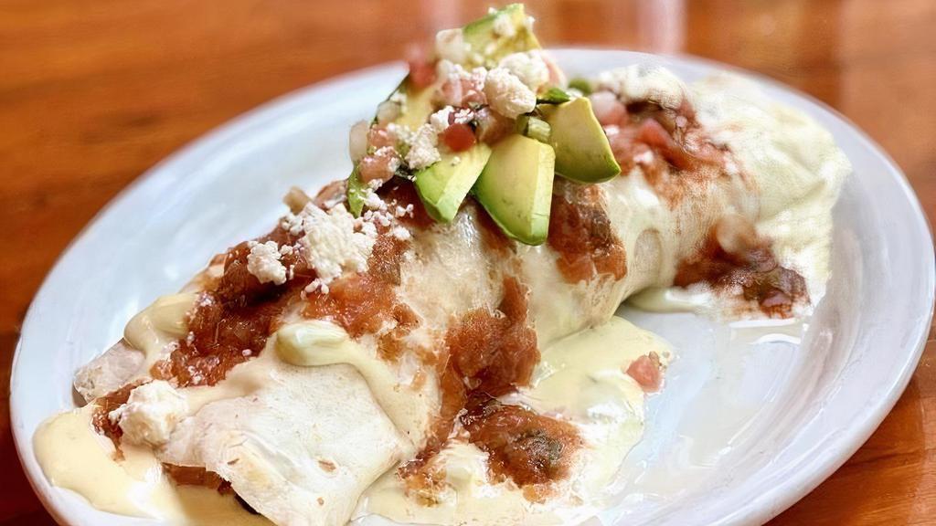 Breakfast Burrito · We put all your favorite breakfast foods in one place:  scrambled eggs, choice of meat, black beans and tator tots wrapped in a flour tortilla.  If that's not enough, we topped it with ranchero sauce, queso & avocado.  Available all day!