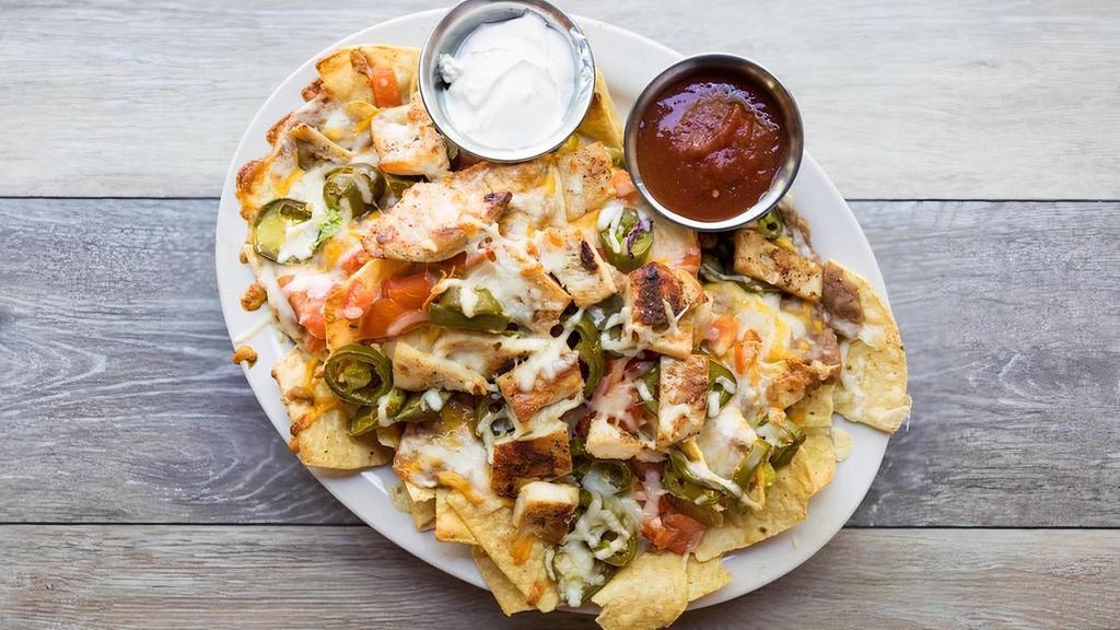 Nachos Grande · Corn tortilla chips topped with refried beans, jack & cheddar cheese, diced tomatoes, pickled jalapeños & choice of grilled chicken, picadillo beef, housemade pulled pork or grilled veggies. Served with sour cream & salsa
