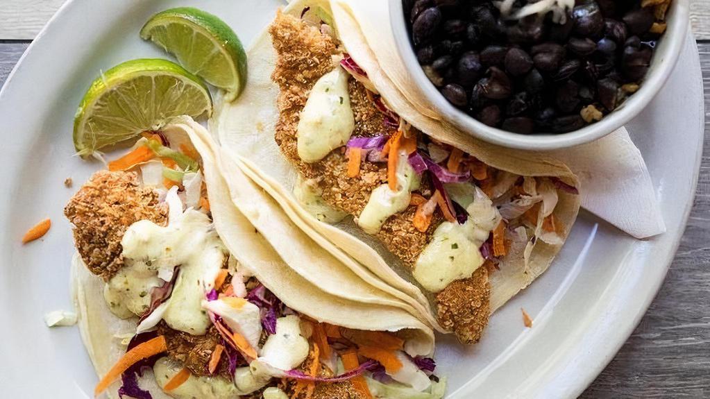 Crispy Catfish Tacos · Two tacos filled with our Texas Tortilla Catfish and shredded cabbage & carrots topped with our signature jalapeno tartar sauce and served with black beans and Mexican rice.  Your choice of flour, corn, or whole wheat tortillas.  You may substitute the beans and rice with one side.