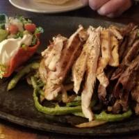 Sizzling Fajitas · Served with grilled onions, bell peppers, guacamole, sour cream, pico de gallo, beans, rice,...
