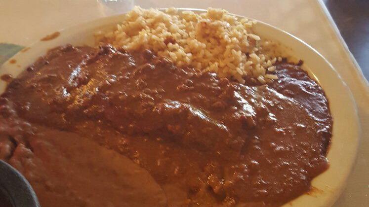 Enchiladas Poblanas · Two chicken enchiladas topped with mole sauce served with rice, beans, and sour cream.