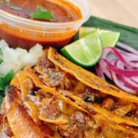 Pork Belly Sisig Birria Tacos · Three corn tortilla tacos bathed in consommé stuffed with Lechon kawali sisig, cheese and gr...