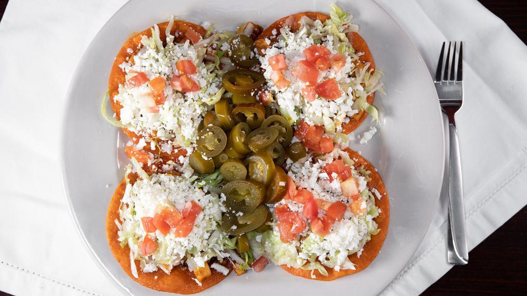 Enchiladas Huastecas · Four small red tortillas topped with chorizo, potatoes, lettuces, tomatoes, and cheese.