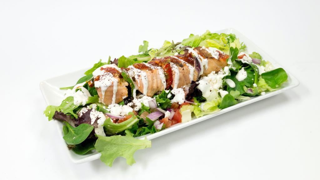 Salmon Kebab Salad · Salmon Kebab over a bed of greek salad, house dressing, yogurt sauce, cilantro sauce, and seasonings!