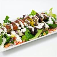 Lamb Kebab Salad · Lamb Kebab over a bed of greek salad, house dressing, yogurt sauce, cilantro sauce, and seas...