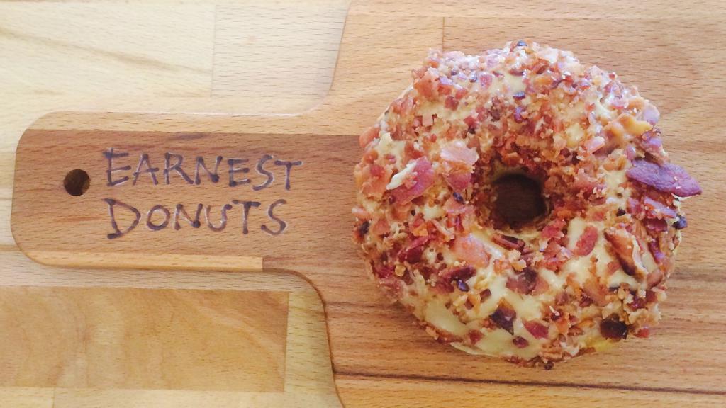 Maple Bacon · Raised donut frosted with maple icing and covered in bacon crumbles (cooked and crumbled freshly in-house).