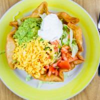 Taco Salad · Flour tortilla shell filled with lettuce, tomatoes cheese, guacamole, and sour cream over yo...