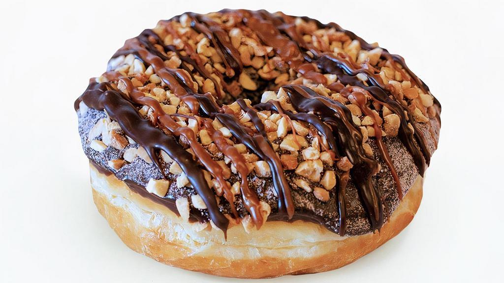 Chuckles · Raised yeast doughnut with chocolate frosting dipped in hot chocolate powder and topped with peanuts and caramel and chocolate drizzle.