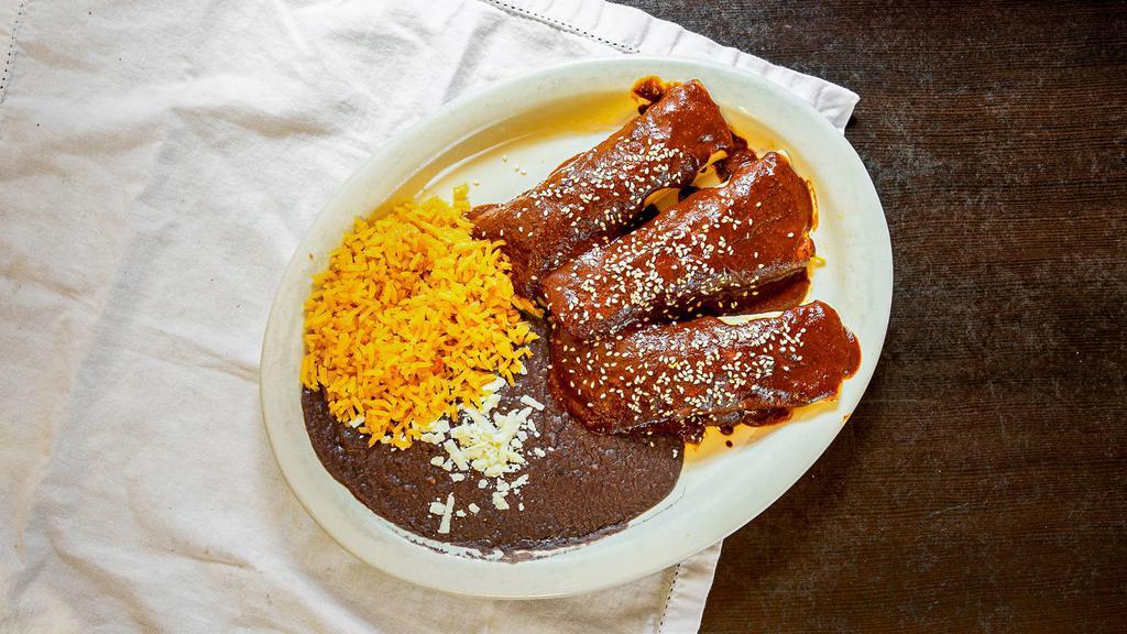 Mole Enchiladas  · Two shredded chicken enchiladas topped with mole sauce. served with rice and beans. beef enchiladas.