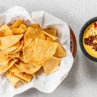 Rockstar Queso + Chips · Queso mixed with ground beef, topped with sour cream and guacamole.