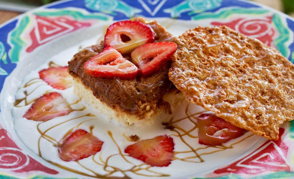 Tres Leches With Fresh Strawberries · Traditional Mexican cake soaked with three sweet creams and served with fresh strawberries and an almond praline lace cookie.