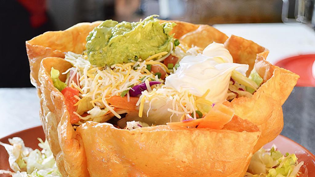 #28 Taco Salad · Tortilla Shell filled w/Beef or Chicken, Lettuce, Tomato, Sour Cream, Guacamole and Cheese. Add fajita for an additional charge.