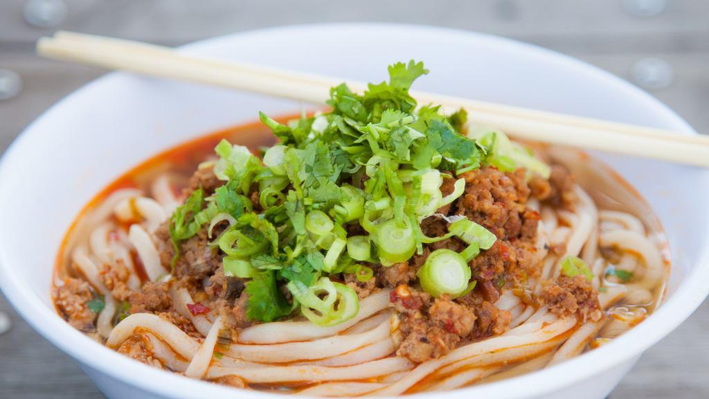 Dan Dan · Ground pork spiked with an abundance of garlic, ginger and scallions. Sweet, savory and spicy! The fresh noodles are finished with a splash of chicken broth and garnished with fresh herbs.