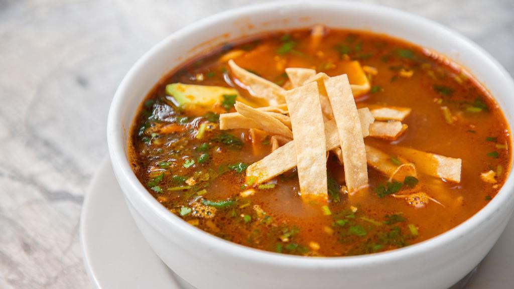 Tortilla Soup · Chicken and tomato broth garnished with sliced avocado, shredded chicken, Chihuahua cheese, cilantro, and tortilla chips.
