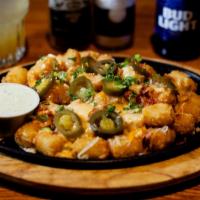 Tater Tot Skillet · Tots loaded with Mixed Cheeses, Queso, Bacon, Jalapeños, Chives & Jalapeño Ranch.