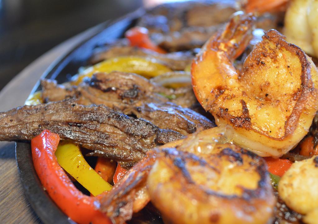 Fajitas Texanas (Lunch) · A combination of chicken, steak, and shrimp. Served with onions, tomatoes, bell peppers, lettuce, tomato, sour cream, guacamole, and flour tortillas on the side. Served with rice and charro or refried beans. *No substitutions