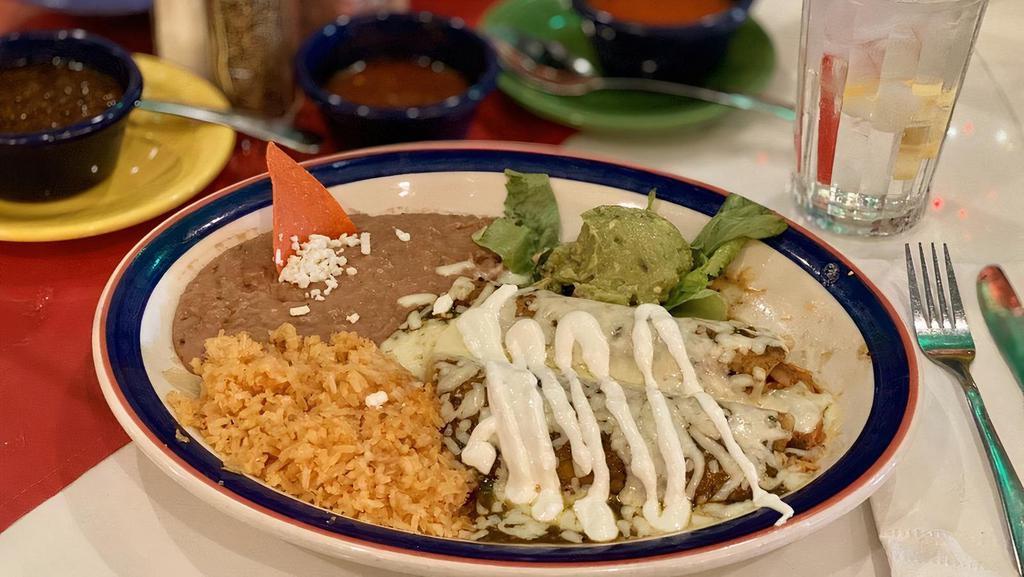 Enchiladas Verdes · [2] Chicken Enchiladas topped with Green Tomatillo Sauce, Monterrey Jack Cheese and Sour Cream. Served with Guacamole, Spanish Rice and Refried Beans