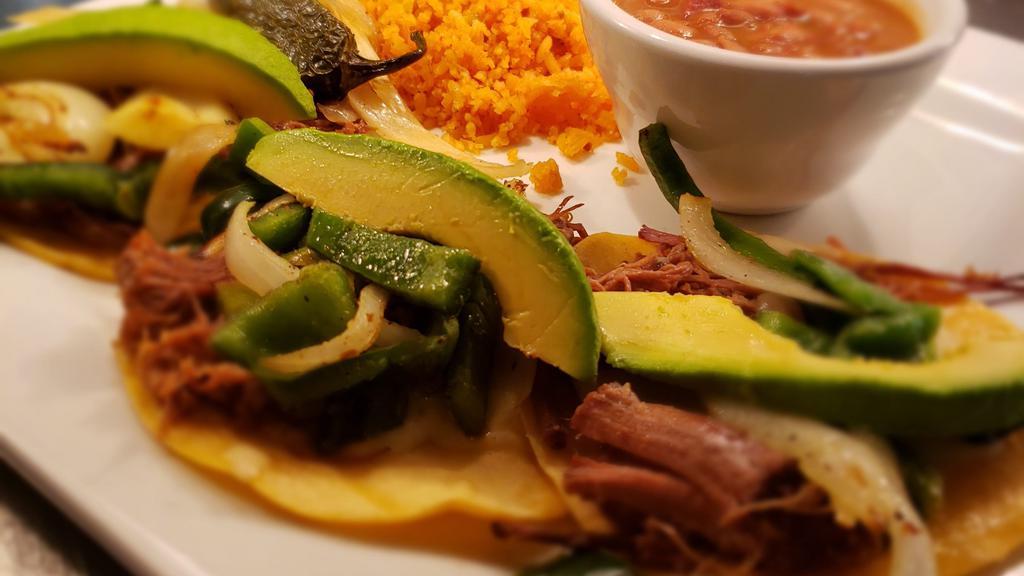 Brisket Tacos · Three soft corn tortillas topped with slow roasted brisket,green onions, monterey cheese and poblano pepper. Served with cilantro, onions, rice and charro beans.