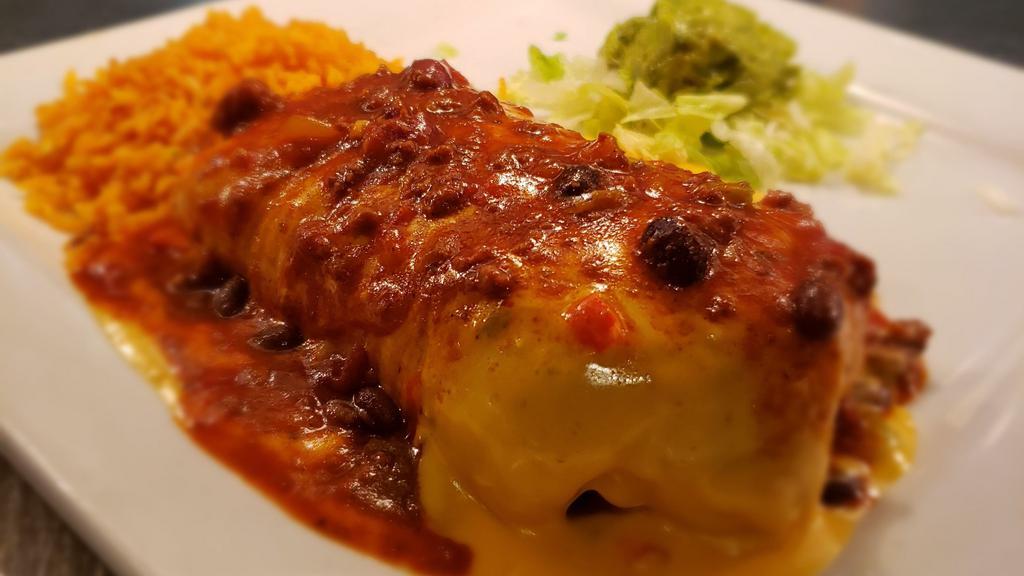 Burrito Dinner · Large flour tortilla filled with seasoned ground beef or shredded chicken, rice and refried beans, then topped with queso or chili con carne. Served with lettuce, onions,  tomatoes, guacamole and sour cream.