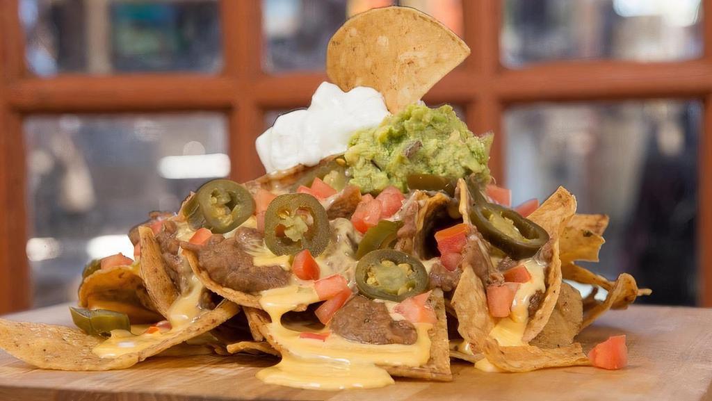 Queso Stacked Nachos · Tortilla chips covered with fresh guacamole, sour cream, jalapeños, tomatoes & Flats Queso