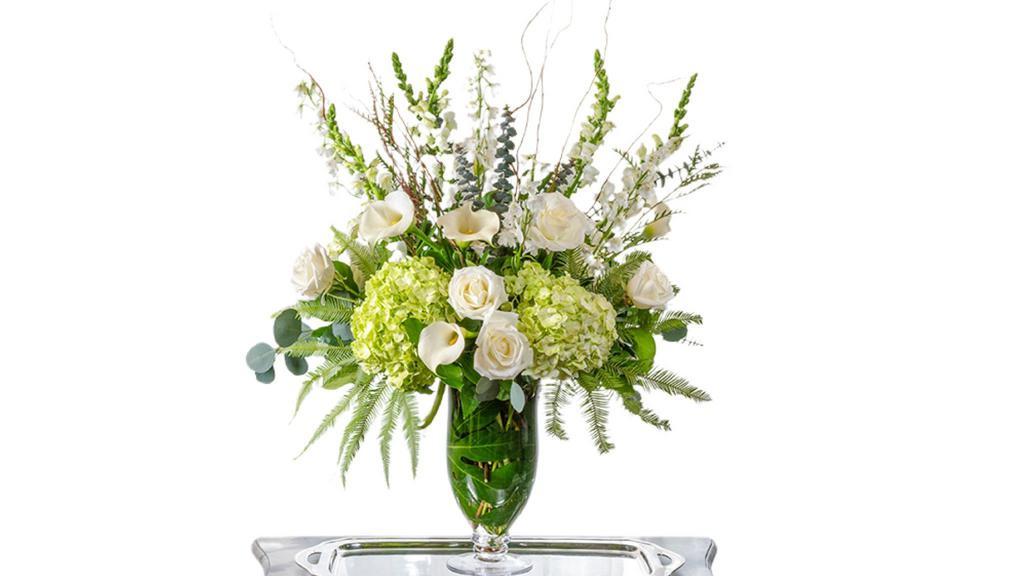 Heavenly  · Classic White and Ivory Premium Blooms with premium greenery and filler in a hurricane glass vase.