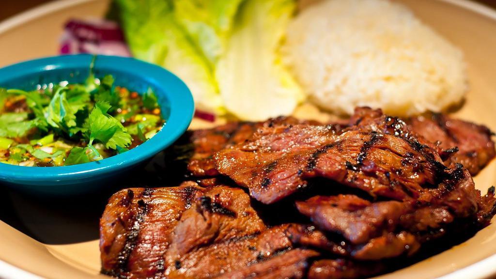 Tiger Cry · 12 oz of USDA CHOICE®, grilled, marinated tender cut beef w/ Mam’s special sauce served w/ sticky jasmine rice & Mam's roasted chili sauce w/ romaine hearts & chopped red onion on the side.