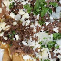 Brisket Nachos · Tortilla chips, refried beans, brisket, BBQ sauce, mozzarella, cheddar, minced onions and ci...