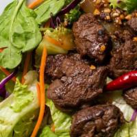 Shaken Beef Salad · Cubed filet mignon sautéed with sweet onions in a mildly spicy marinade over fresh assorted ...