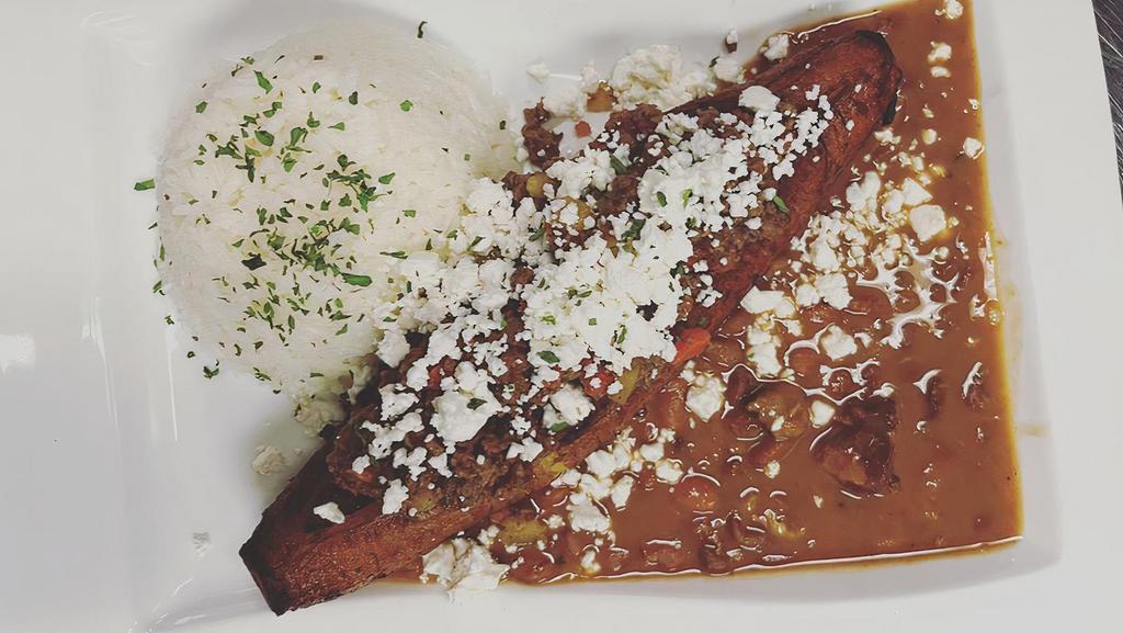 Canoa De Platano · Deep fried sweet plantain stuffed with picadillo topped with cheese, garnished with cilantro. Served with rice and beans.