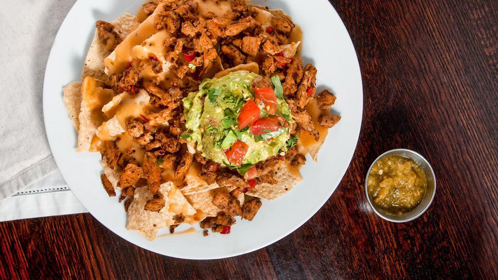 Chik'N Nachos · Local, non-gmo tortilla chips covered with chik'n, bell peppers, onions, queso & guacamole