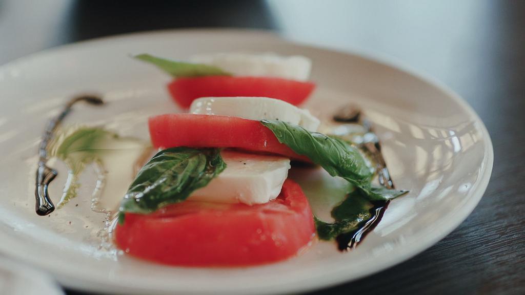 Tomato Caprese · Heirloom tomatoes tossed with fresh basil, balsamic vinegar, extra virgin olive oil, and mozzarella di bufala.