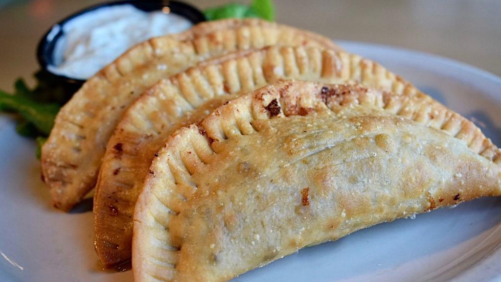 Empanadas · 3 soft dough empanadas filled with seasoned ground beef and cheddar cheese. Deep fried to a golden brown and served with a side of cilantro mayo sauce for dipping.