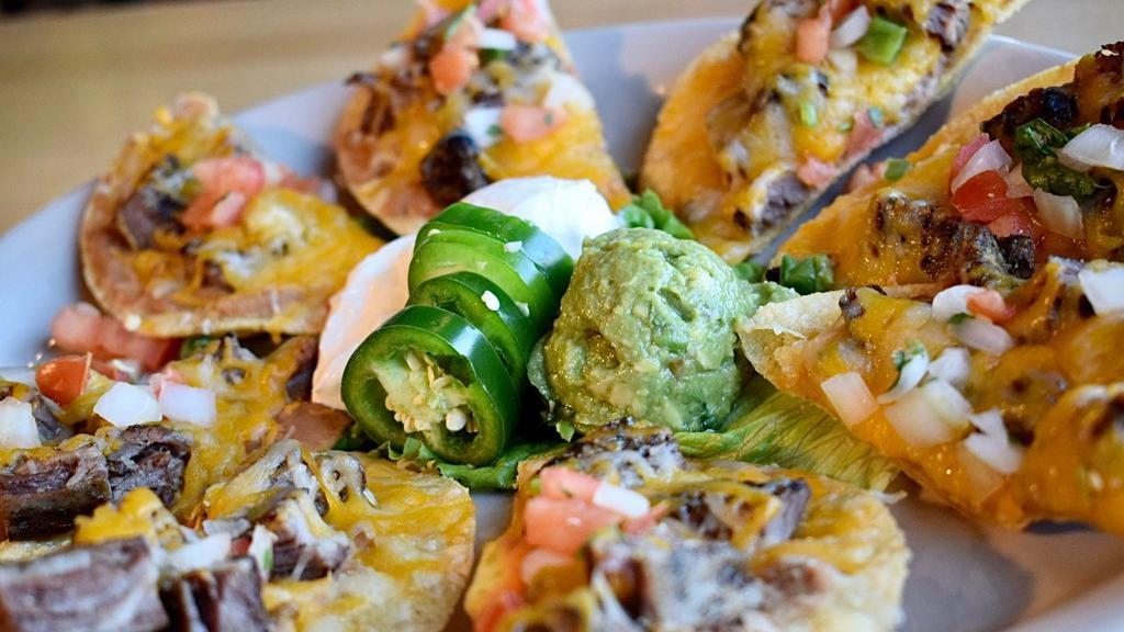 Fajita Nachos · Traditional Nachos topped with refried beans and either fajita steak or chicken, melted cheese and pico de gallo. Served with guacamole, sour cream and jalapeños.