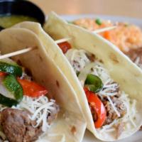 Brisket Tacos · Two slow cooked brisket tacos topped with grilled onions, poblano peppers and jack cheese. S...
