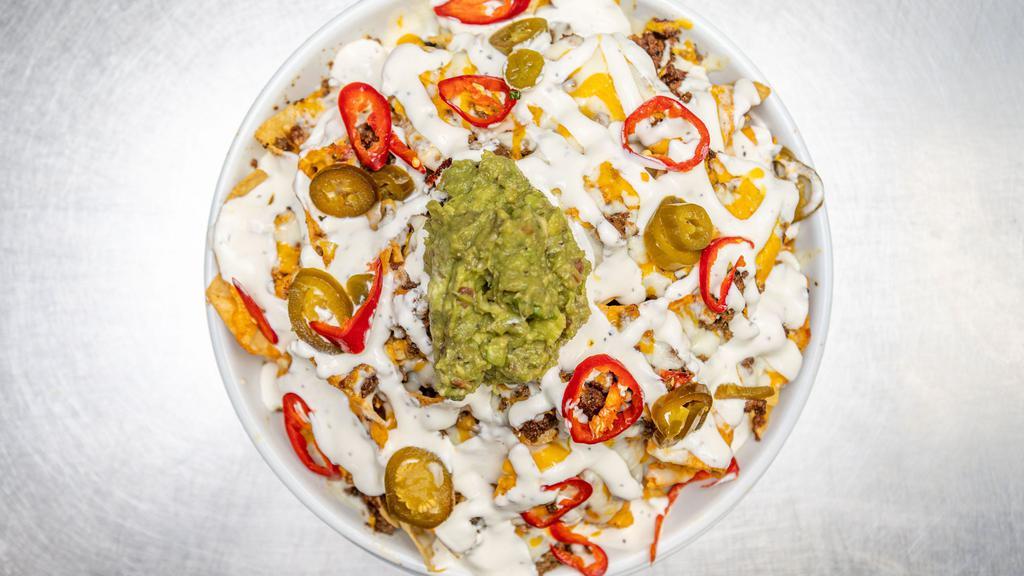 Stacked Nachos · House chips layered with queso blanco, shredded cheddar, seasoned ground beef, jalapeños, guacamole, sour cream & Fresno chili's.