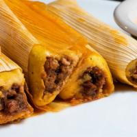 Original Tamales · Three tamales topped with gravy and cheese.