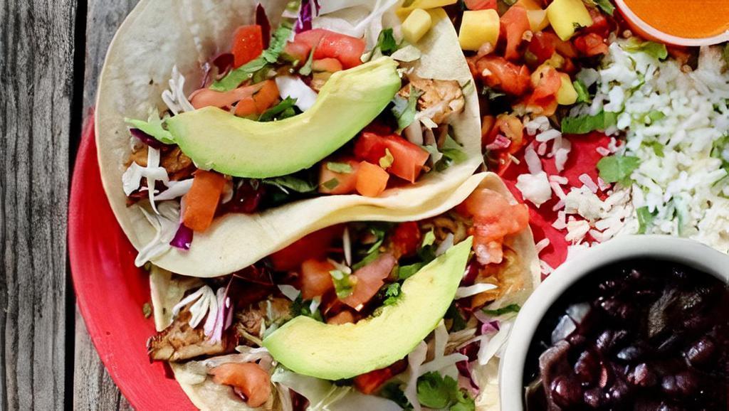 Acapulco Fish Tacos · Gluten-free. Two flour or corn tortillas filled with your choice of fried or grilled tilapia topped with shredded cabbage, sliced avocado, fresh cilantro, and tomatoes. Served with cilantro lime rice, black beans, and mango pico de gallo.
